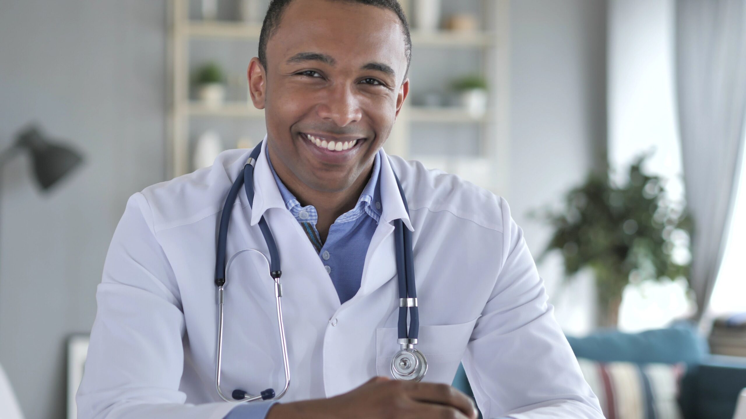 Smiling individual in a white coat with a stethoscope